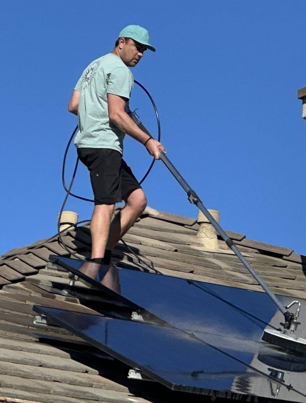 man on roofing cleaning solar panels