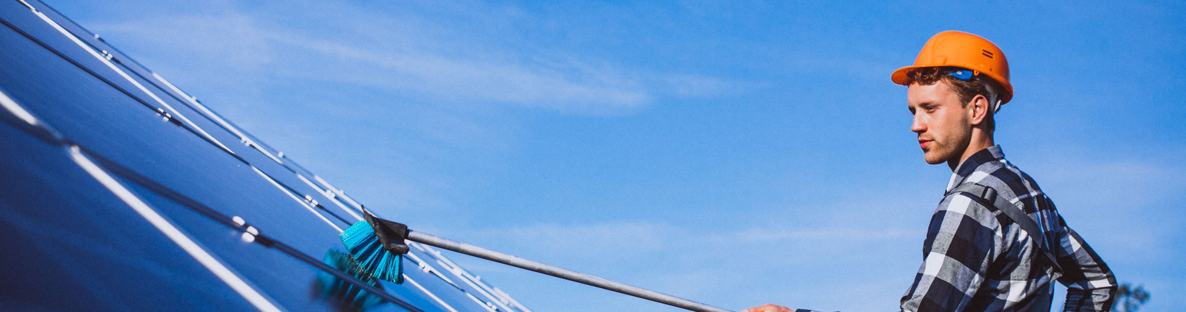 man cleaning a solar panel with a long metal brush